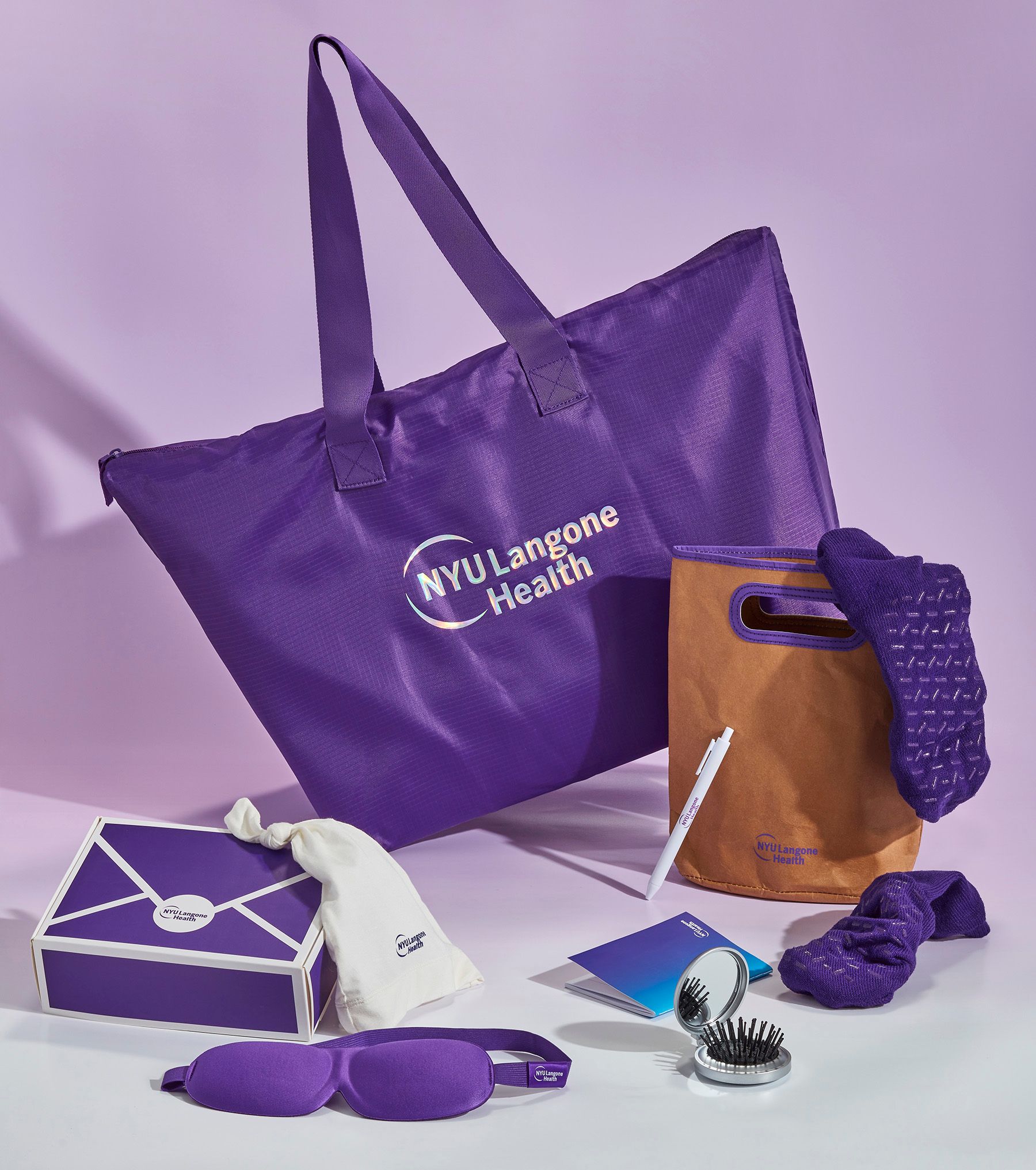 Branded merchandise created by Twelve for NYU Langone; purple branded canvas tote bag, brown branded cooler bag, sleep accessories, pens, custom packaging, collateral